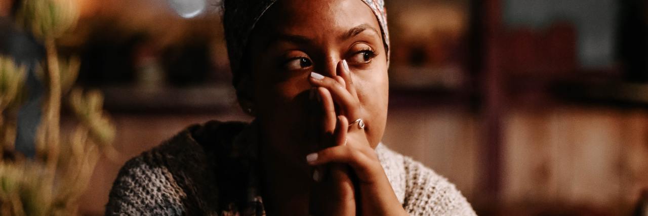Self-Care Doesn't Work for Me as a Black Woman photo of woman sitting at table, looking off-camera and thinking