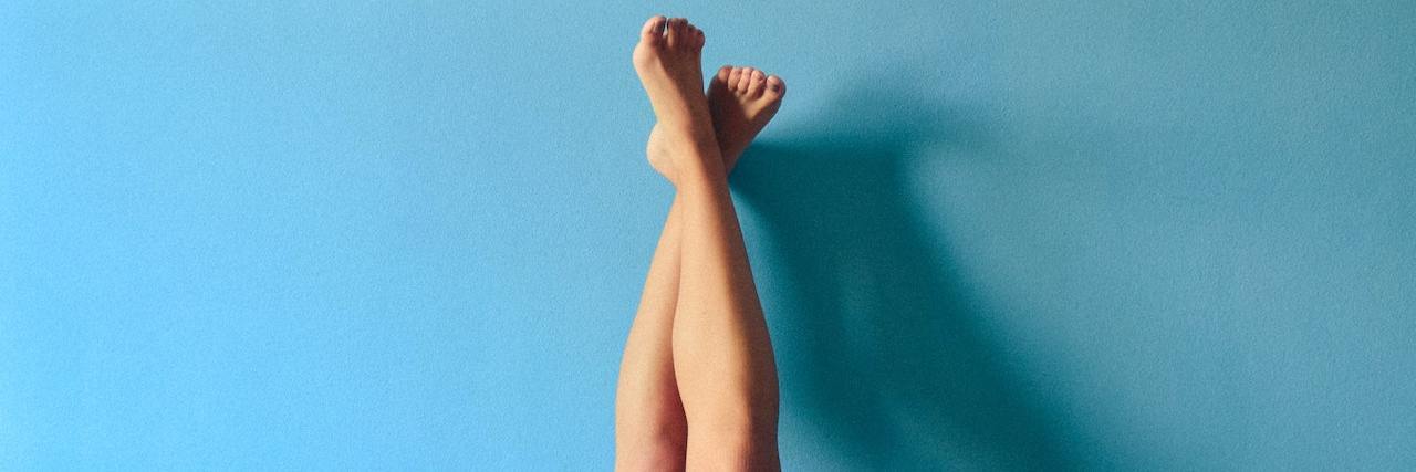 Living With an Eating Disorder, I'm Not Comfortable in My Body legs up against a blue wall