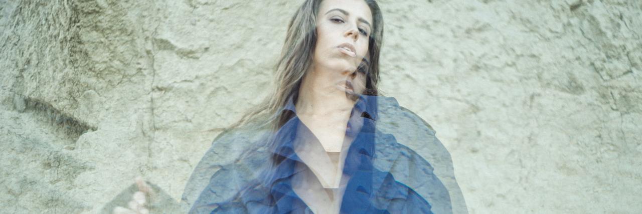 photo of woman against wall looking into camera with multiple exposures overlaid so that she is blurred multiple times downwards