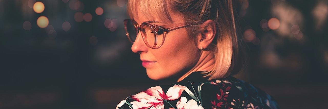24 Ways Trauma Can Affect Your Personality woman looking behind her holder, wearing glasses