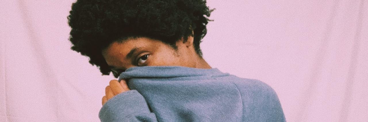 What People Who Experience Pain Daily Wish Their Friends Knew A woman covering up her face with a sweatshirt