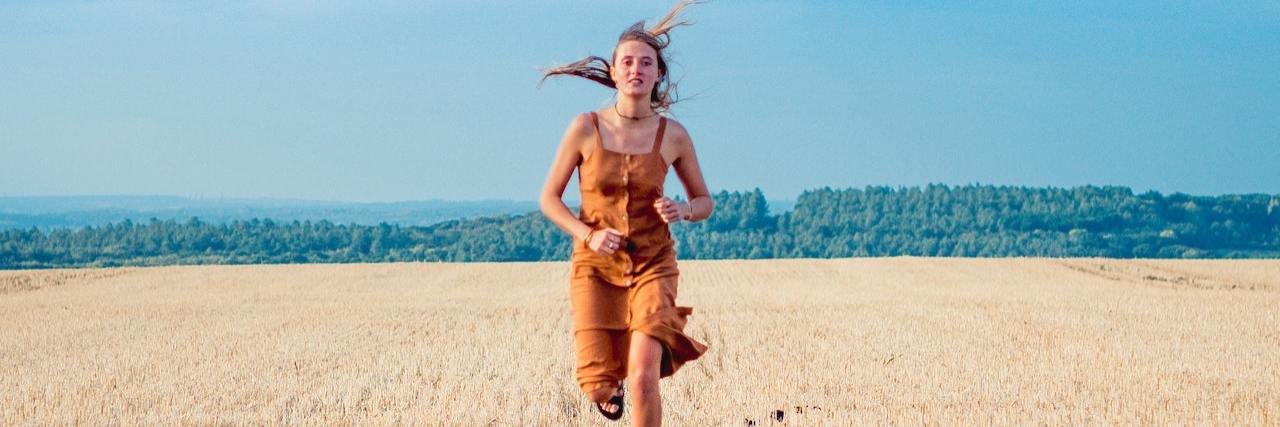 A woman funning through a field