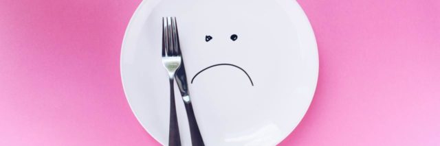 A frowny face on a plate with a fork and knife