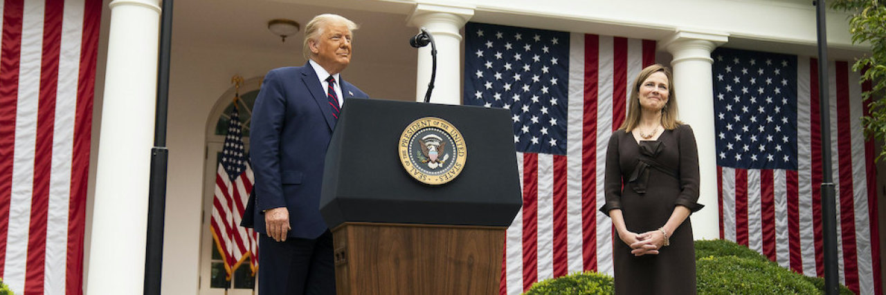 Donald Trump and Judge Amy Coney Barrett standing in the rose garden in the white house. Trump stands behind a podium