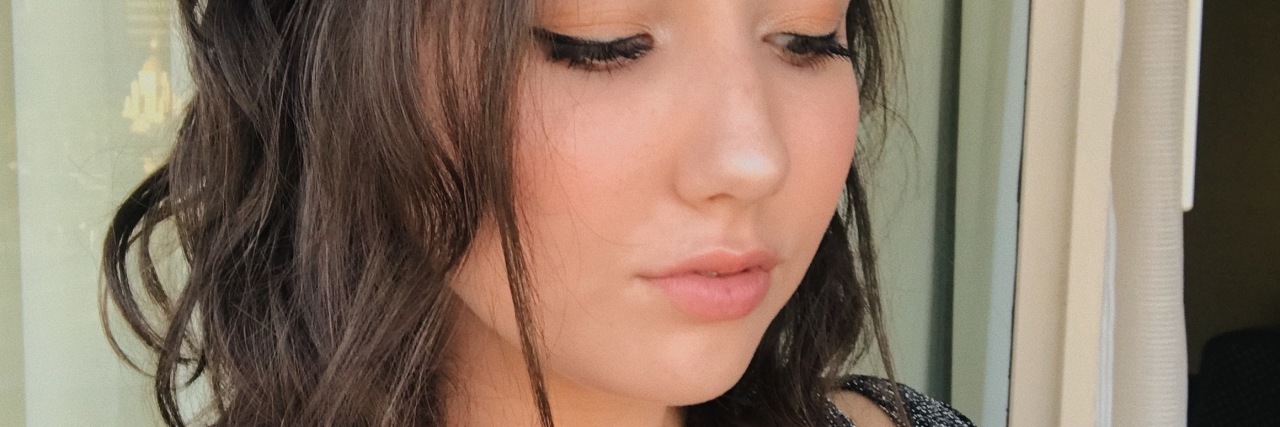 My Therapist Invalidated My Trauma Struggle photo of the contributor standing in front of a window with her eyes closed, looking upset