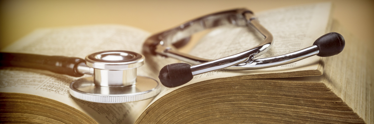 Stethoscope on an old book of medicine.