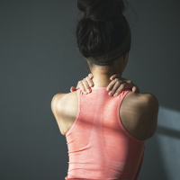 A woman holding her shoulders as if in pain