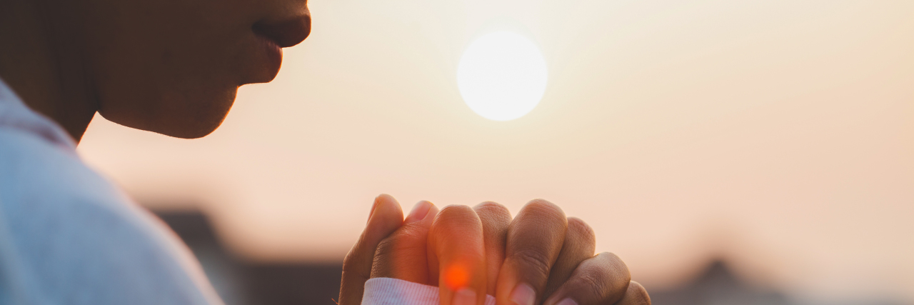 How Grief Can Transform After Your Child's Life-Limiting Diagnosis  woman with hands clasped, morning sun in the background