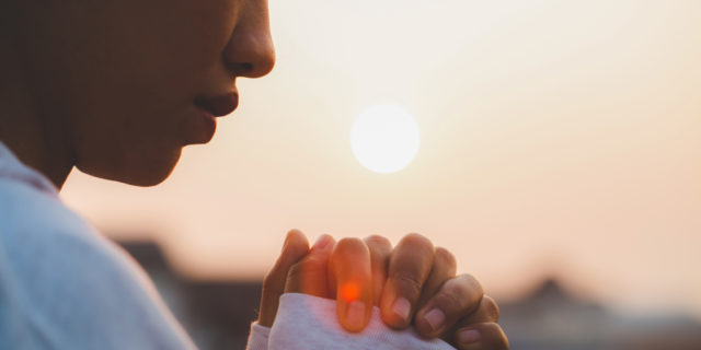 How Grief Can Transform After Your Child's Life-Limiting Diagnosis  woman with hands clasped, morning sun in the background