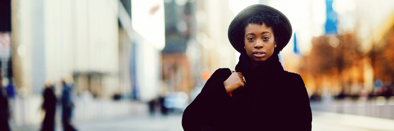 PTSD: Feeling Guilty Because Your Trauma Isn't 'Enough' A woman wearing a big black coat standing in the street