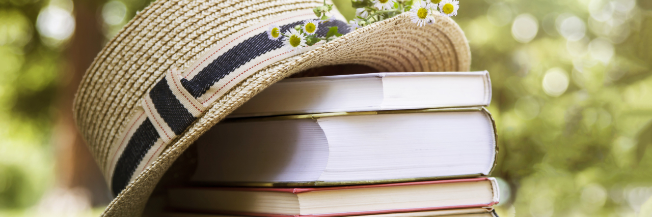 5 Books That Helped Me With Anxiety, C-PTSD, and Toxic Relationships a straw hat sitting next to a stack of books
