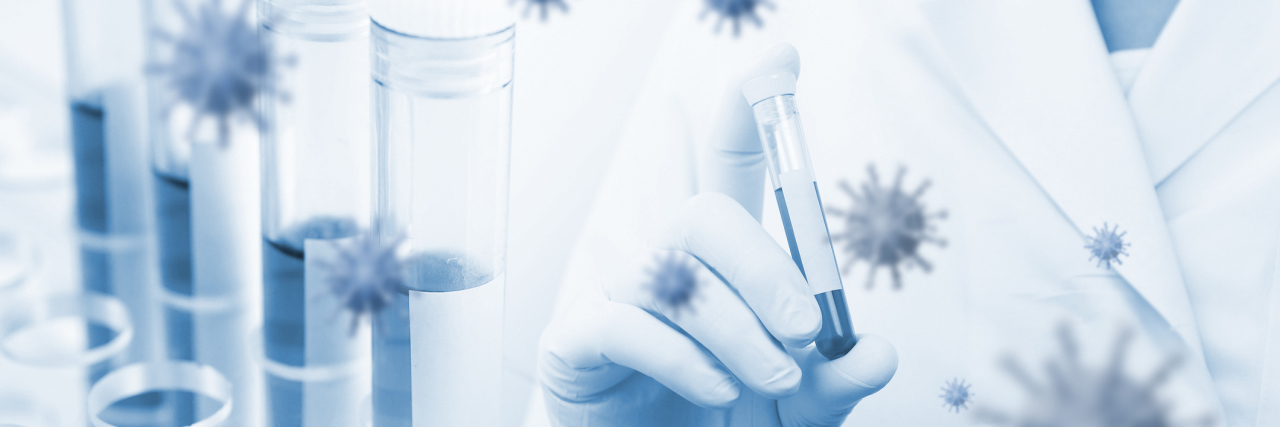 5 Things to Know About a COVID-19 Vaccine Person in a white lab coat holds a vial filled with blue liquid in their gloved hand