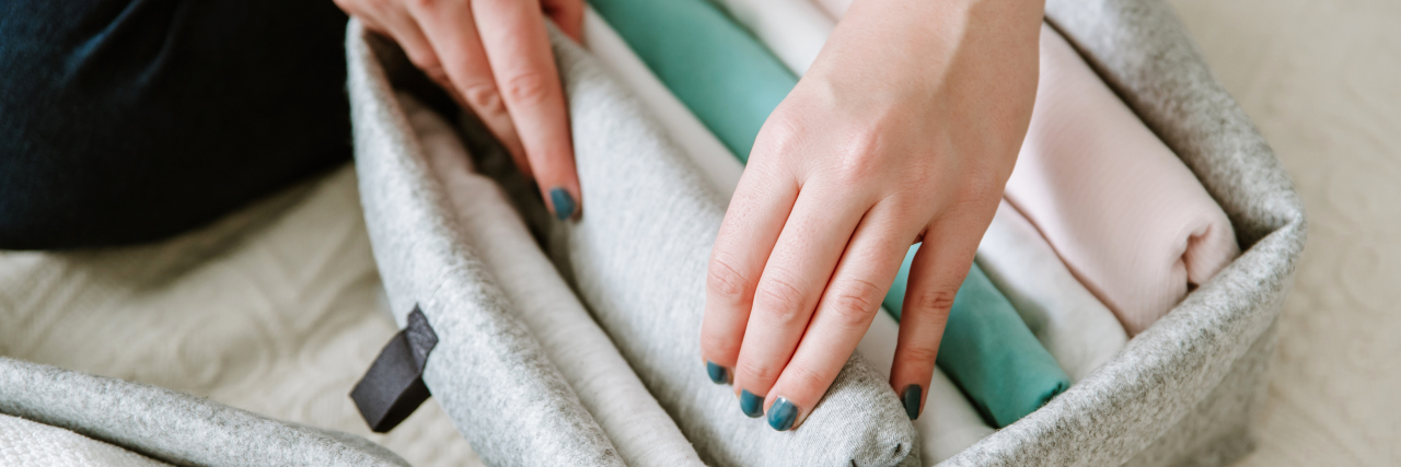 When I Finally Got Rid of My 'Skinny' Clothes a woman's hands going through a box of clothes