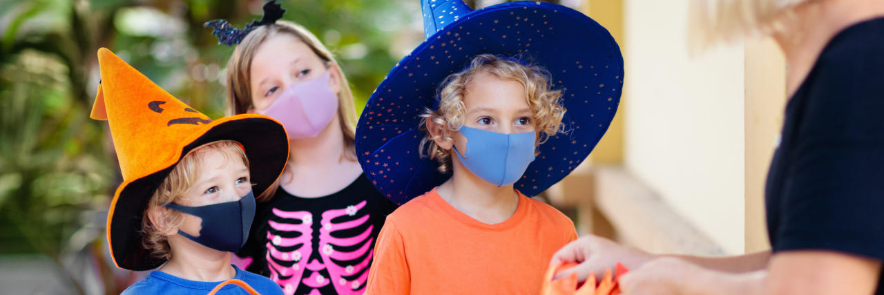 Making Halloween About Kindness During the COVID-19 Pandemic Kids trick or treat in Halloween costume and face mask.