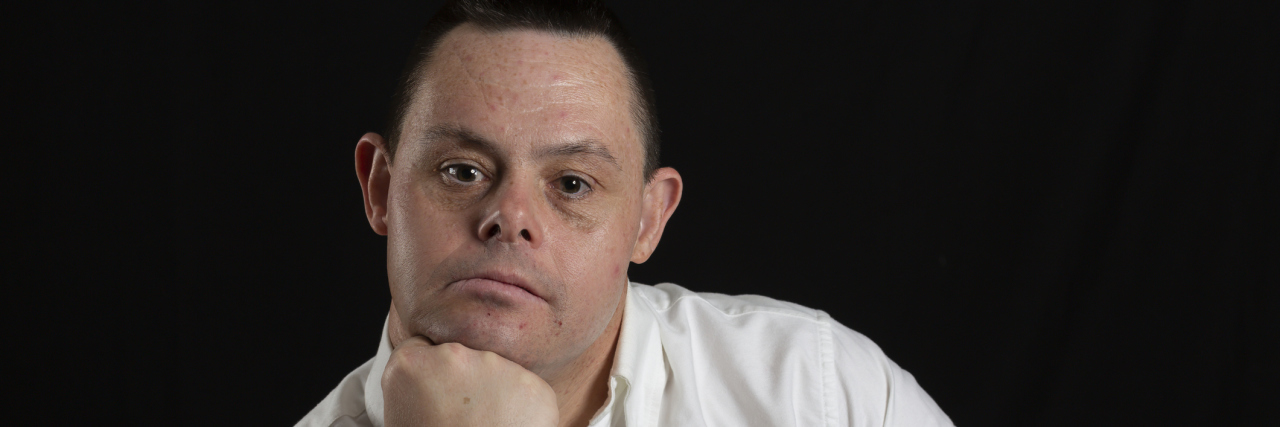 man with down syndrome in photo studio on black background