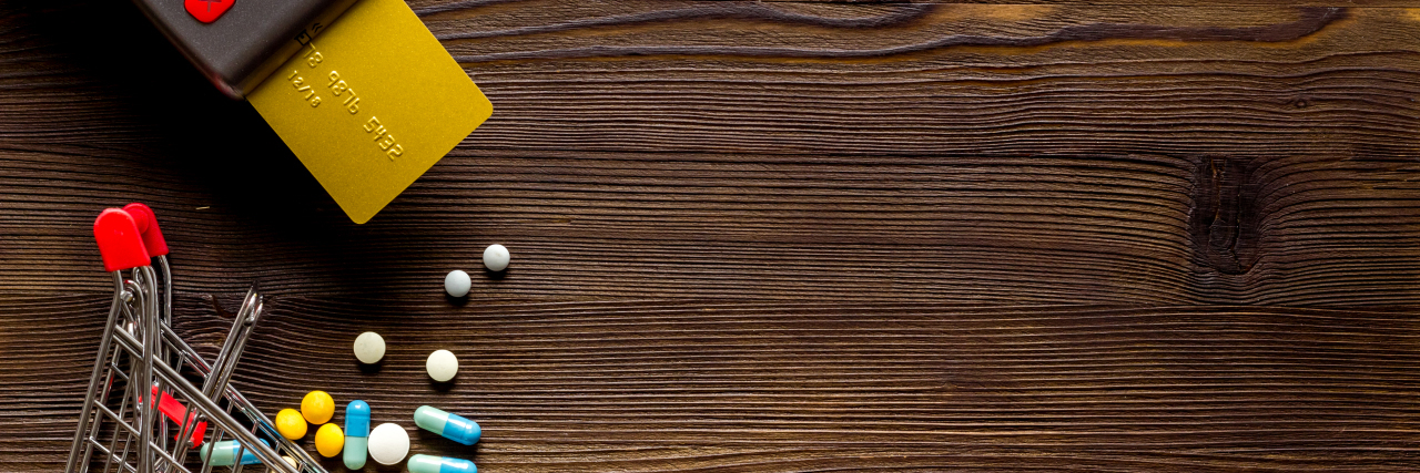 How Wealth and Income Impact the Health of People With Disabilities image of a credit card in a reader, and a mini shopping cart with pills spilling out