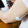woman checking glucose level and dosing insulin using insulin pump and remote sensor on her hand, focus on foreground