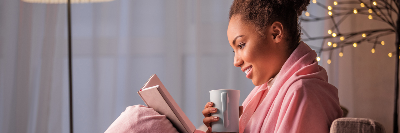 Woman drinking coffee and reading a book.
