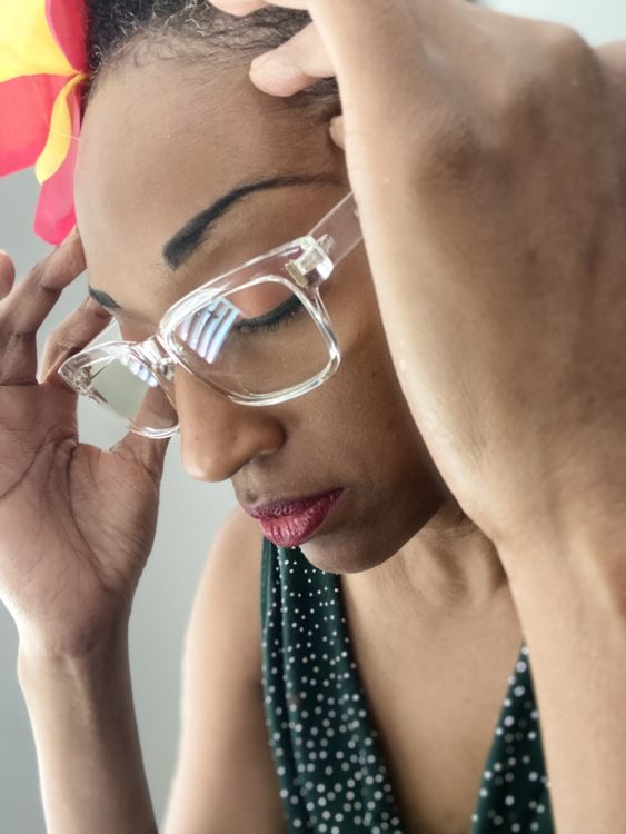 a woman with glasses with her hands on her temples