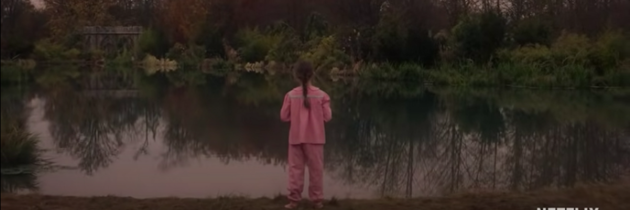 How Netflix's 'The Haunting of Bly Manor' Represented Trauma Young girl wearing pink pajamas looks out over a creepy lake surrounded by trees