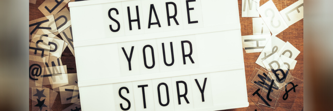 Share Your Story text on the lightbox with plastic alphabets scattered on wood background
