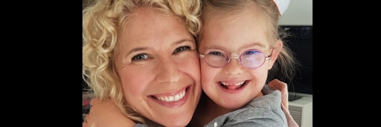 When My Daughter With Down Syndrome Interrupted My On-Camera Interview A girl with Trisomy 21 hugging her mom