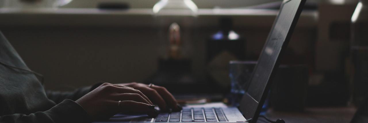 Remote Jobs for People With a Disability or Chronic Illness Hands typing on an open laptop setting on a table in front of a window