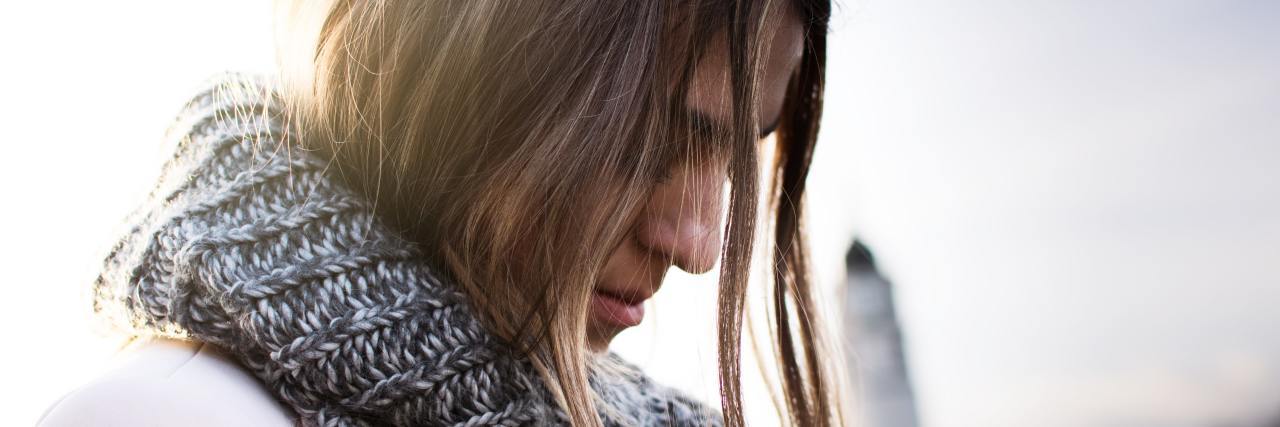 My Borderline Personality Disorder Reaction to Dating Rejection photo of woman with sun behind her, eyes closed and looking down with hair partly covering her face