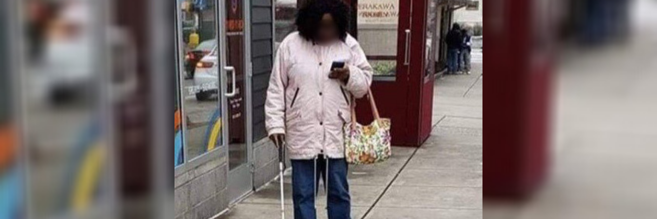 We Need to Talk About This Photo of a Blind Woman Using Her Phone African American woman with white cane looking at her phone.