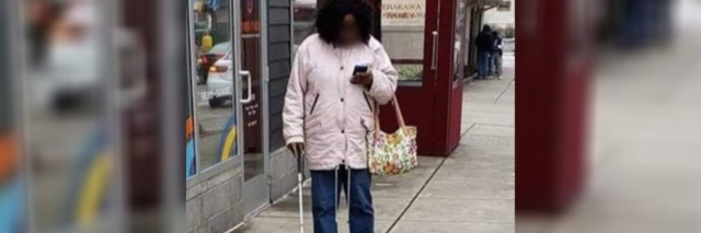 African American woman with white cane looking at her phone.