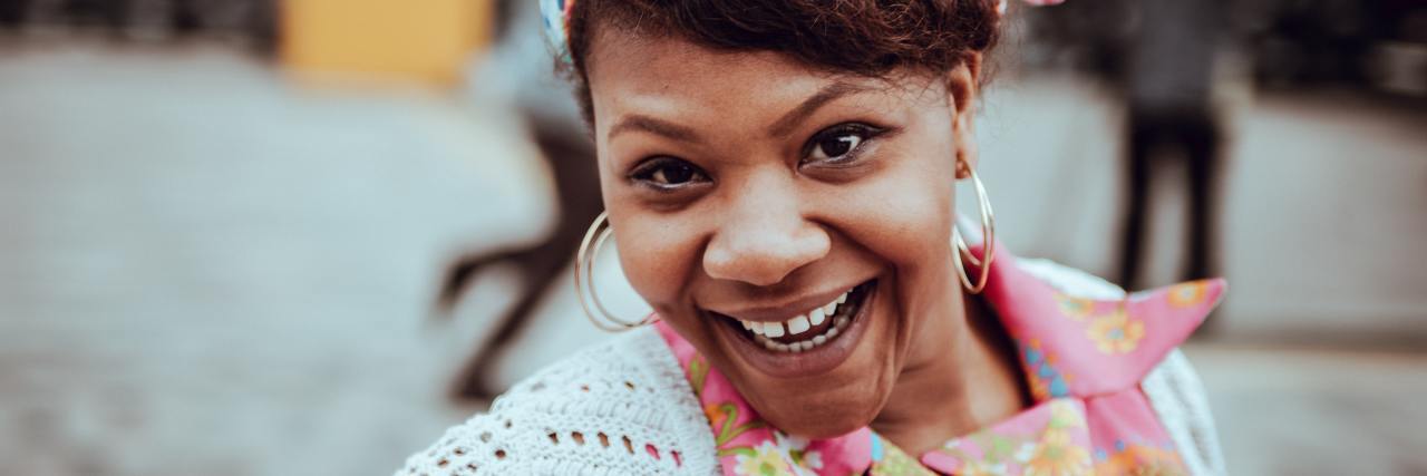Fun and Simple Ways To Challenge Anxiety Thoughts photo of a woman in a colorful top and headband smiling into camera