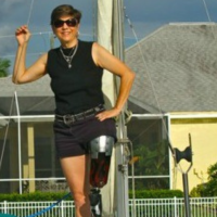 Deb standing on a boat. Her prosthetic leg is visible.