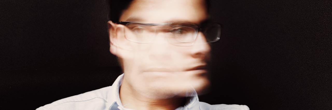A man shaking his head. He's wearing glasses and his face is blurred out.