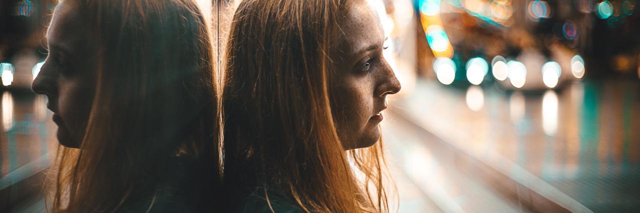 What Life Is Like 6 Months After My Suicide Attempt photo of woman leaning back against mirrored wall, looking upset, with blurred background