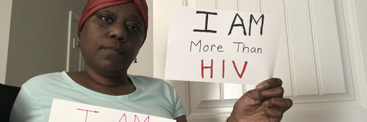Discovering My Calling in Life When Living With a Chronic Illness photo of contributor holding two signs, one saying "I am human" and one saying "I am more than HIV"