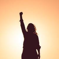Silhouette of woman with her fist raised in the air.