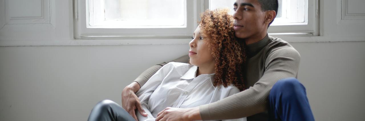 Relationship Boundaries During the Coronavirus Pandemic photo of couple sitting close together on floor near window