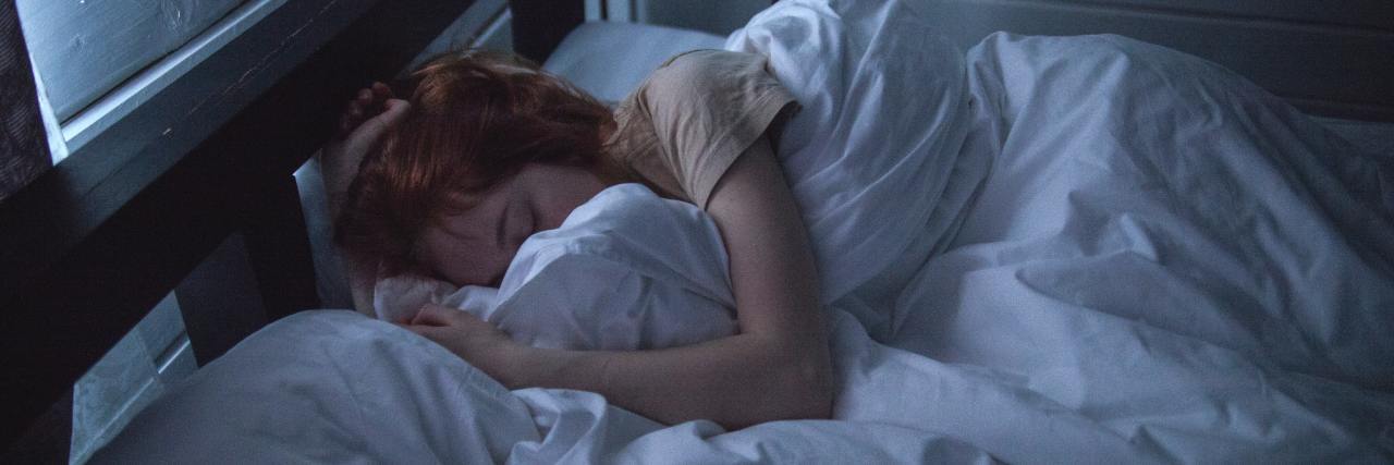 My Morning Routine With the Physical Symptoms of Depression photo of a woman sleeping in bed with duvet covering face