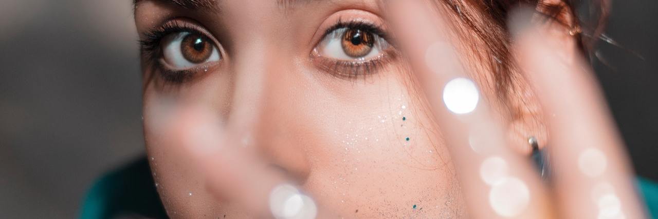 A Mental Health Essay for Creative Overachievers A woman with her hand out, blocking part of her face