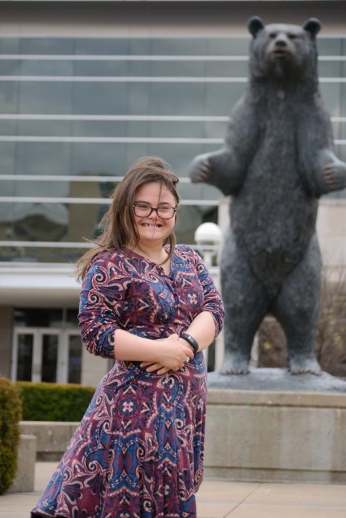 Rachel posing outdoors with a bear statue.