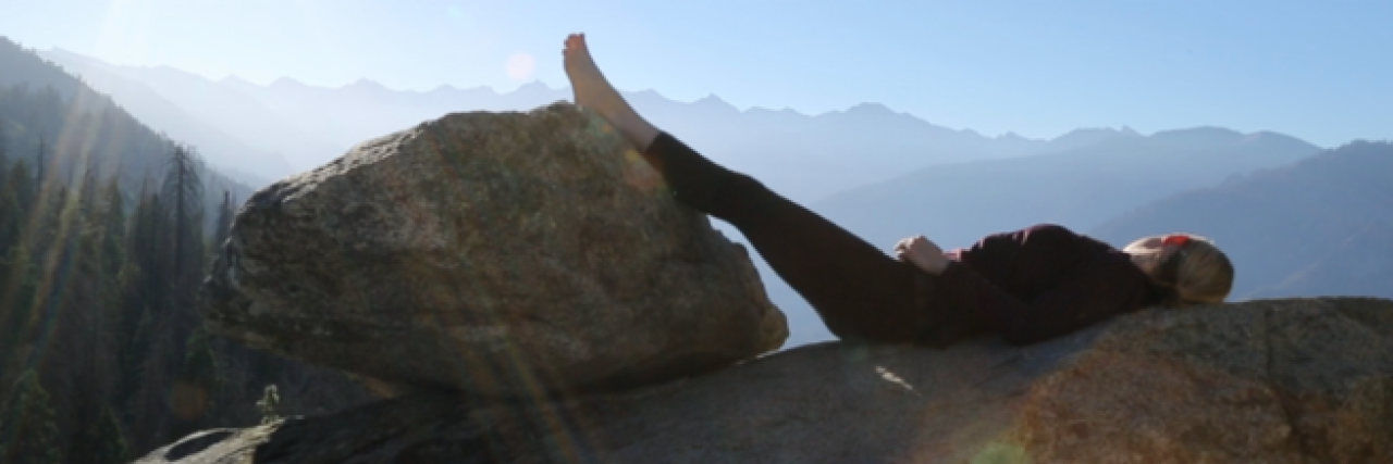 Woman looking out over mountain view with feet resting on a rock
