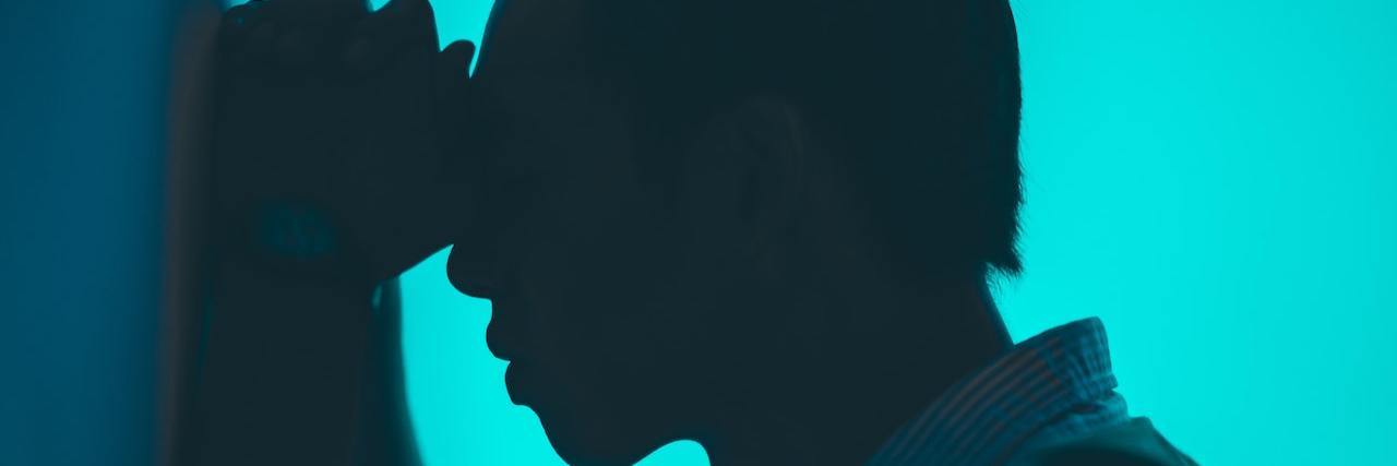 What Are the Different Types of Bipolar Disorder? Profile of a man leaning against a wall looking distressed