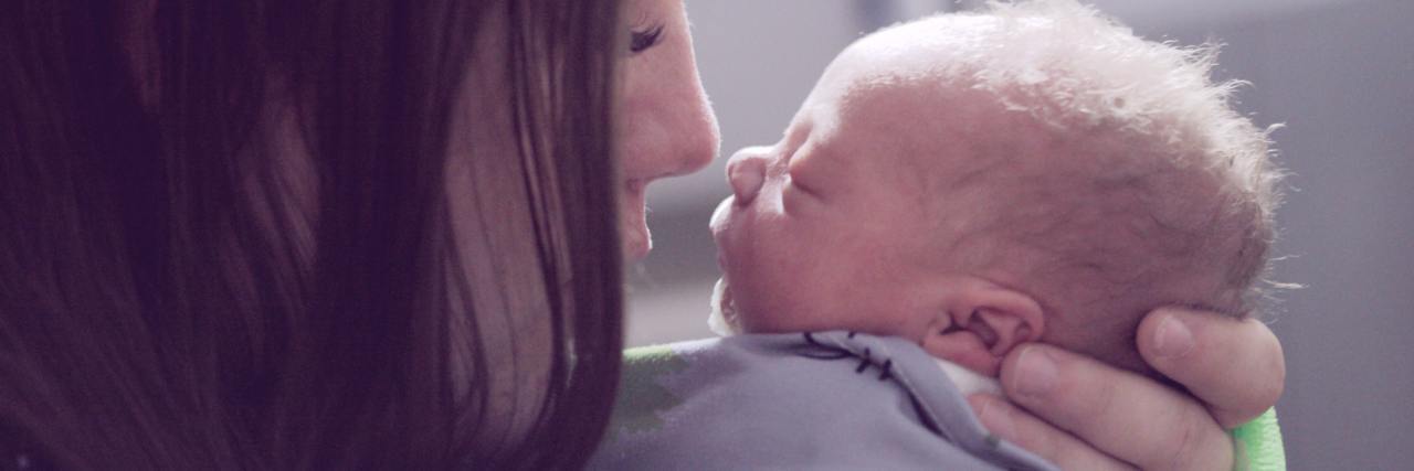 Postpartum OCD: I Was Scared My Baby Would Die in Horrific Ways photo of a mother with a tiny newborn baby holding baby to her face, her eyes closed