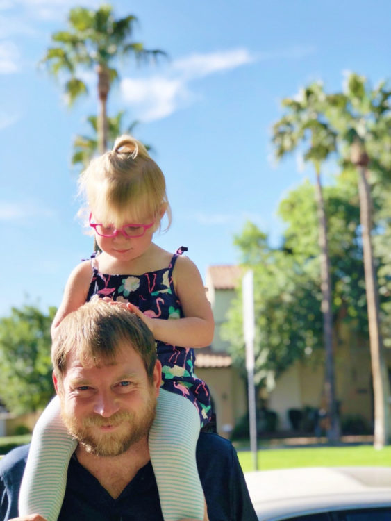 sloane, wearing pink glasses, sitting on top of her father's head