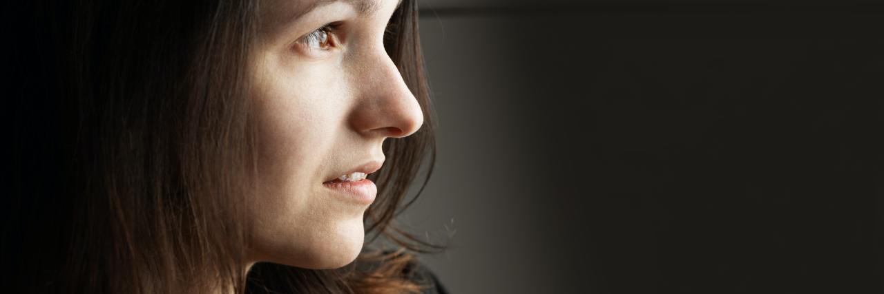 How to Overcome Fear of Relapse With Bipolar Disorder photo of woman in profile view with hand raised to her chest, looking into distance