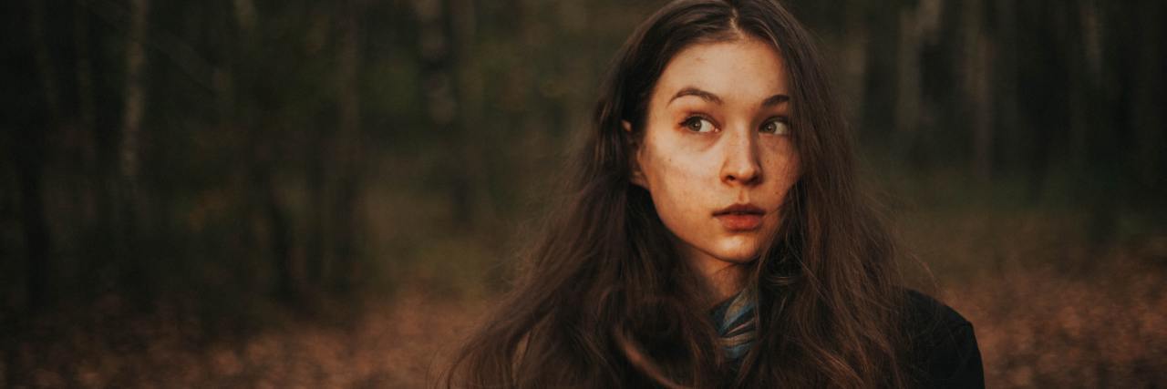 Signs You Need To Stop Ignoring Your Mental Health photo of woman in the woods looking off to the side