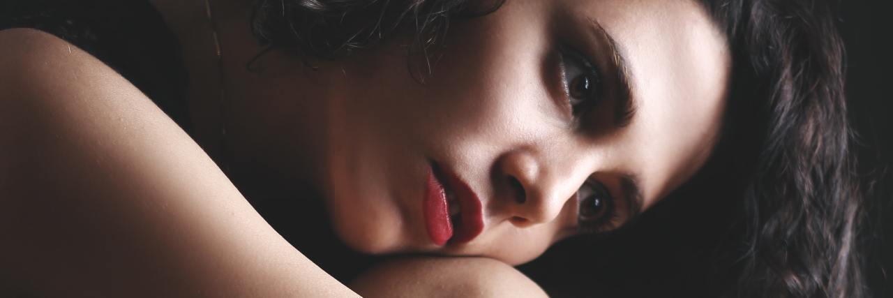 How to Overcome the Fear of Emotional Intimacy photo of woman with dark hair hugging knees and looking off into space