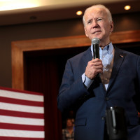 Flickr image from Gage Skidmore, showing President-Elect Joe Biden with a microphone standing beside an American flag
