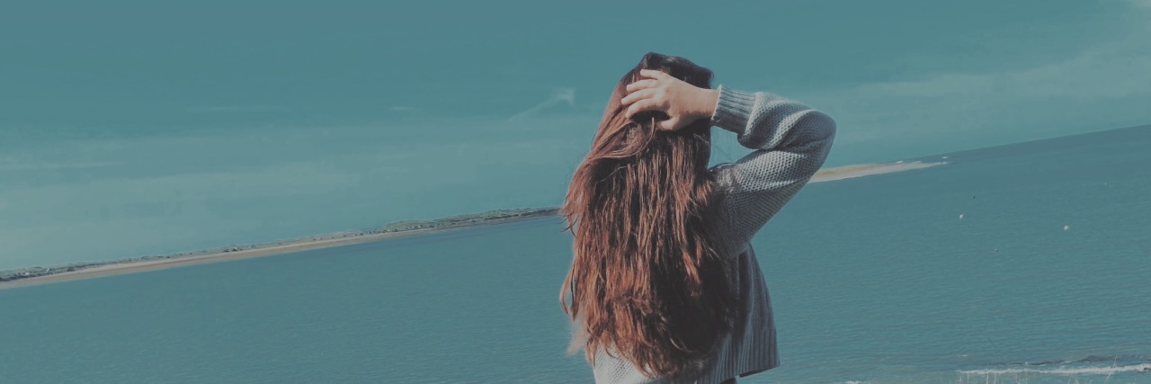 Why We Need More Disability and Disfigurement Representation Charlotte Victoria standing on a mountaintop.