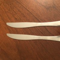 A pair of butter knives on a wooden table.